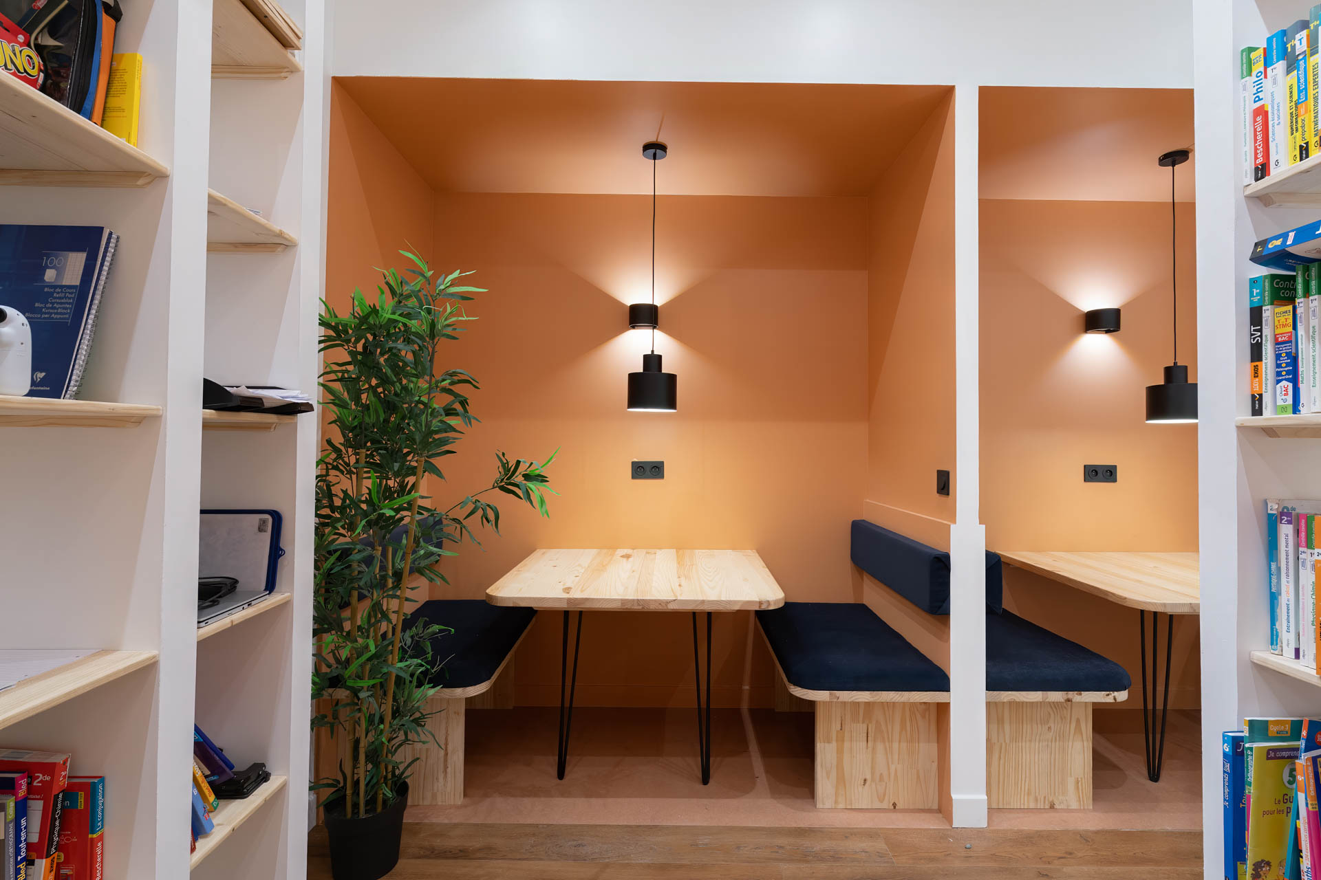Photographie d’un espace de travail aménagé avec bureaux, bibliothèque et éclairage chaleureux